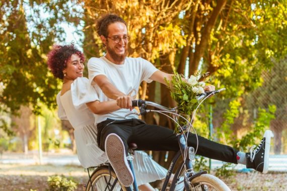 a man and a woman riding a bicycle in a park